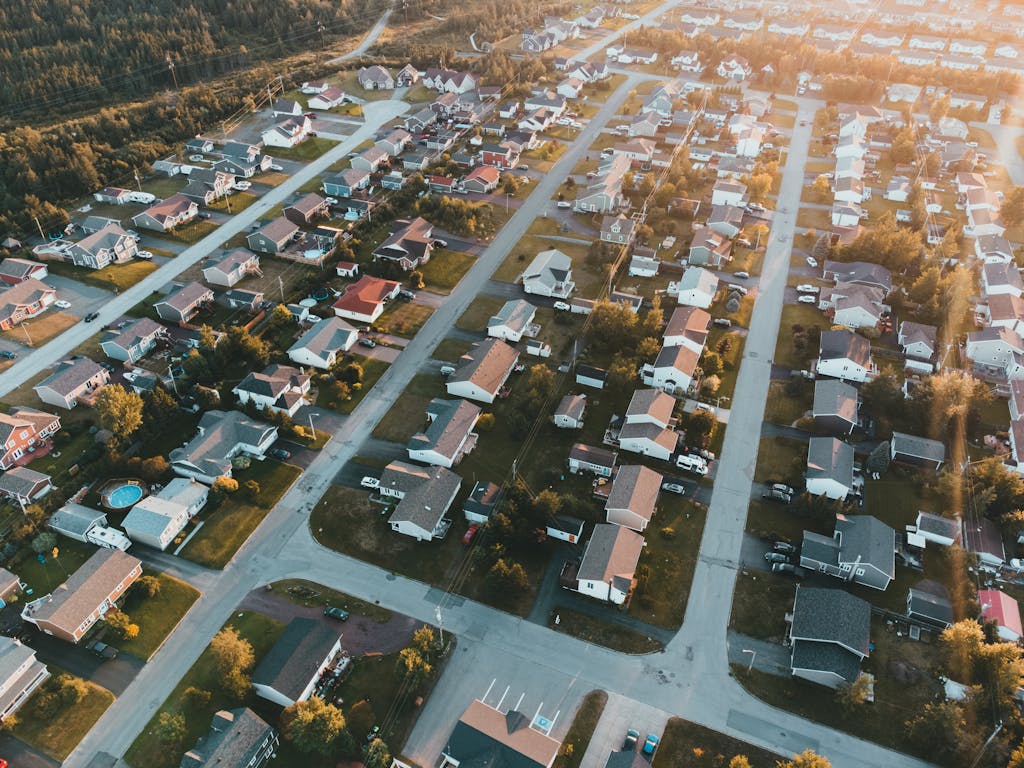 A stunning aerial view of a peaceful suburban neighborhood at sunset with lined houses and streets.