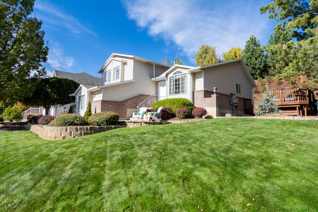 Beautiful suburban house with a manicured lawn, framed by trees and blue sky.