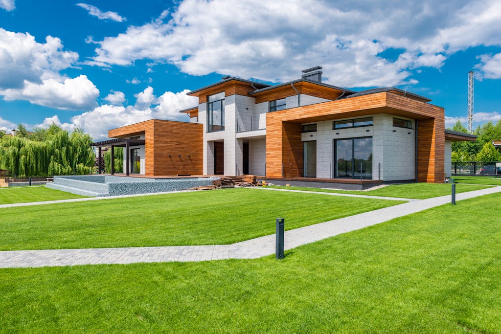 Exterior of contemporary residential house with green yard and paths near forest in summer